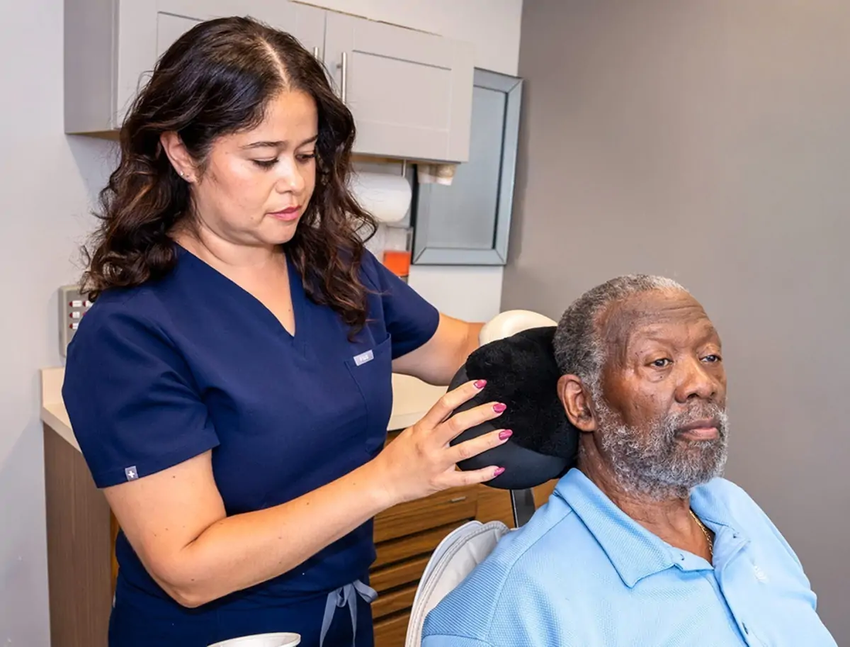 A dental assistant helps a patient feel comfortable on a dental chair