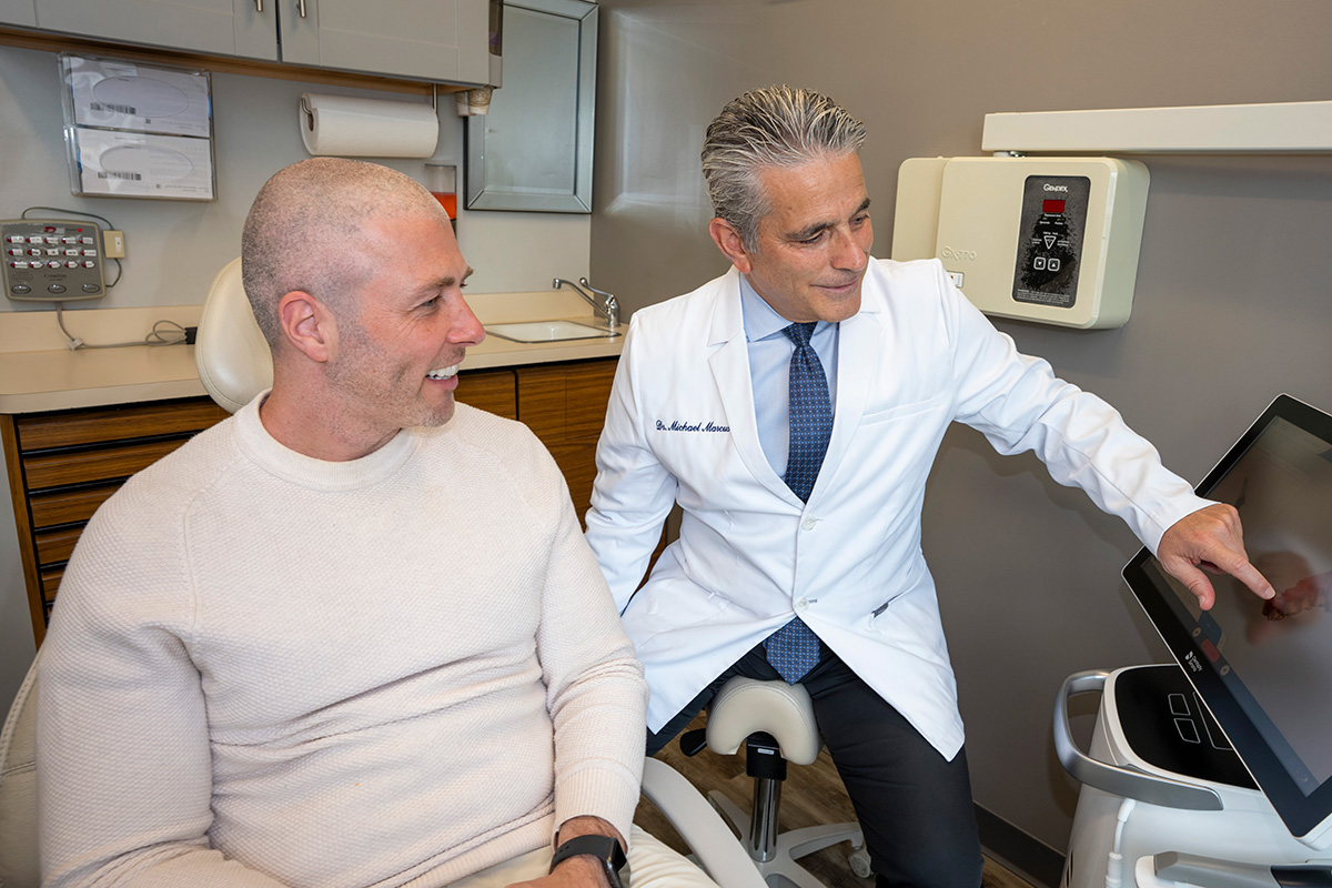 Dr. Marcus showing his patient a 3D teeth model on a scanner