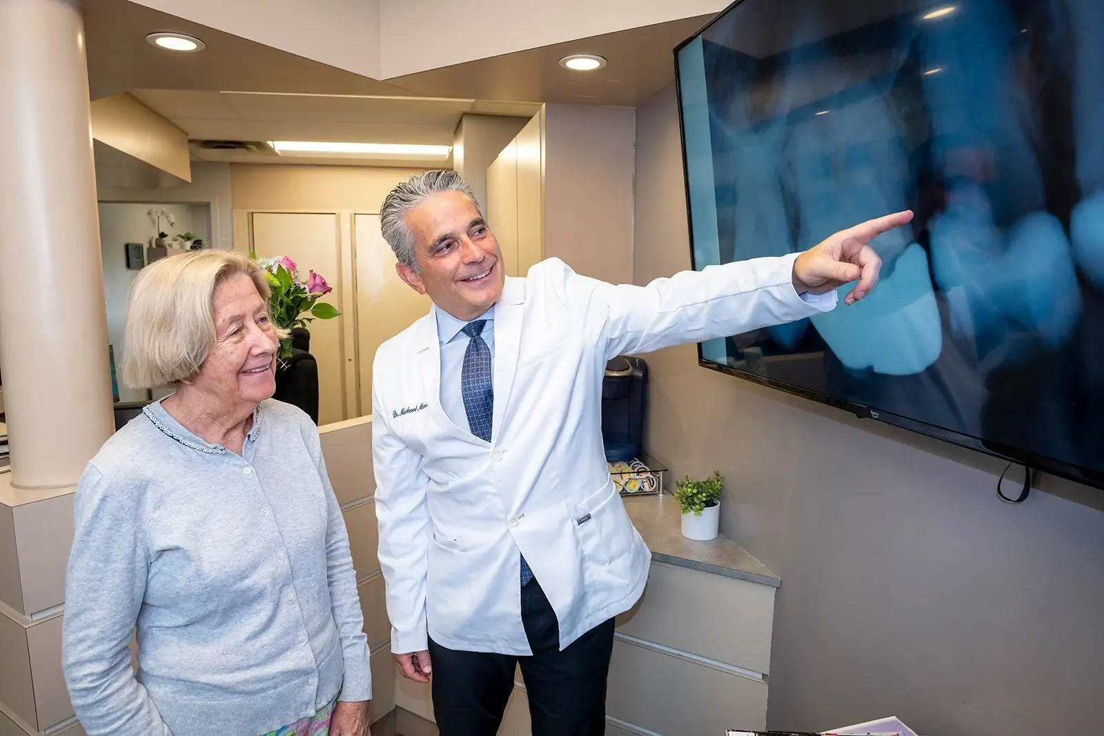 Dr. Marcus pointing to an X-ray image with a patient